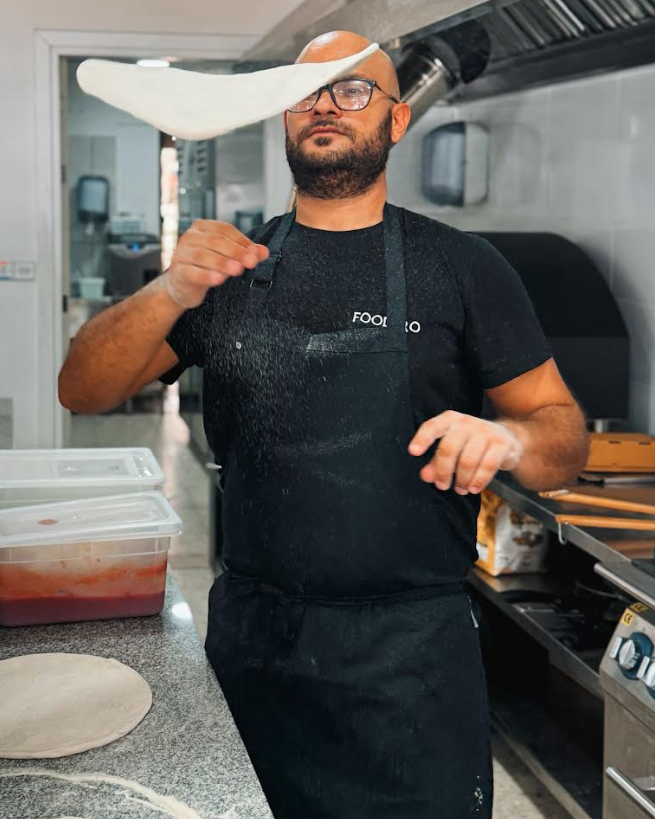 Chef Mario Ruggeri tossing pizza dough in the kitchen